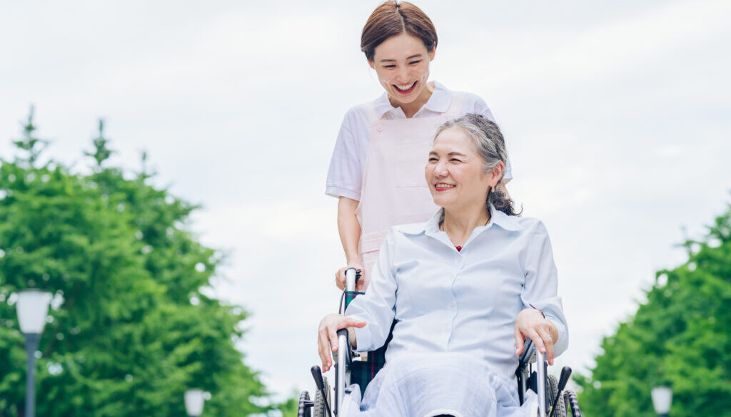 A woman in a wheelchair and young woman in an apron to care for